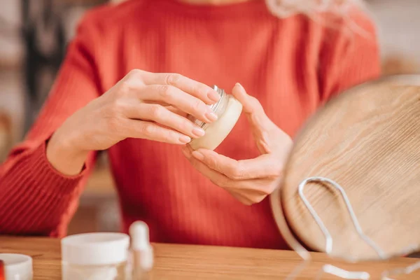 Close of a woman in red holding a jar of cream — Stock Photo, Image