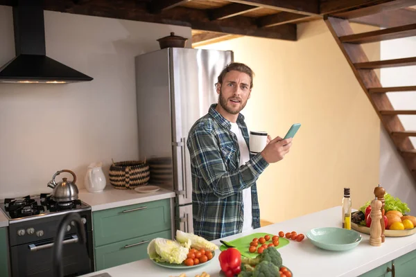 Smiling man texting with his friend while cook — Stok Foto