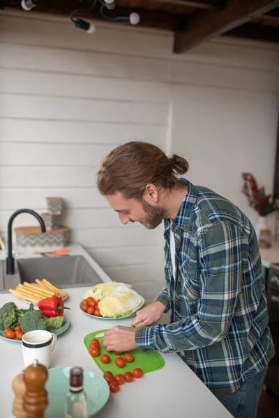Чоловік нарізає вишневі помідори для свіжого салату — стокове фото