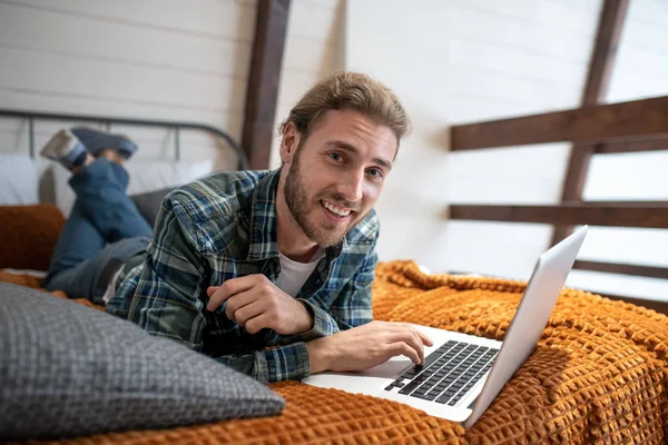 Smiling man working with the computer in his bed — 스톡 사진