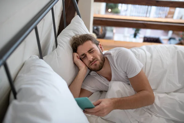 Homem atualizando seu feed usando seu smartphone enquanto acorda — Fotografia de Stock