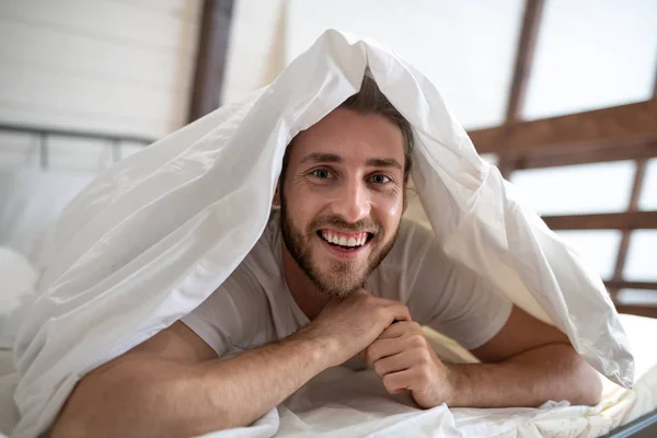 Young bearded man having fun in bed in the morning — 스톡 사진