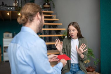 Adam endişeli kadına zarf veriyor.