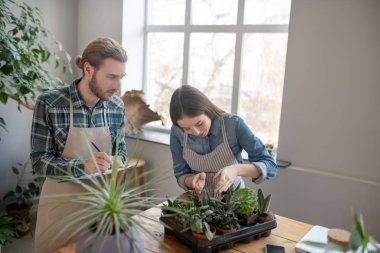 Bir erkek ve bir kadın tesiste sulu şeyleri kontrol ediyorlar.