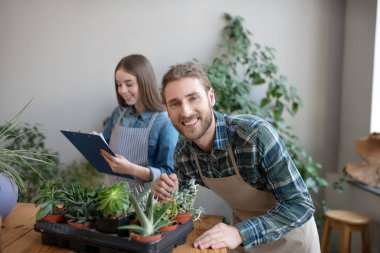 Gülümseyen adam en sevdiği bitkilerle ilgileniyor.