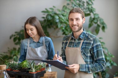Gülen adam bitkileri hakkında notlar alıyor.