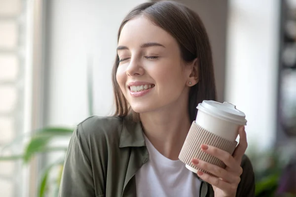 Glimlachende vrouw die plezier heeft tijdens het drinken van koffie in de ochtend — Stockfoto