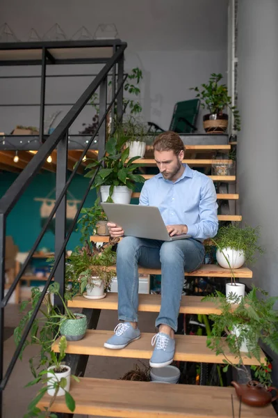 Man zittend op de houten trap met zijn laptop — Stockfoto