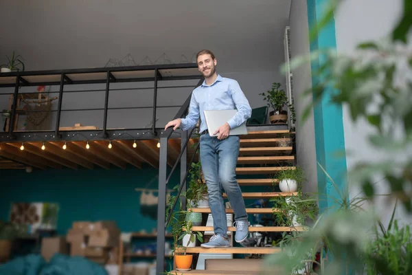 Man standing on stairs holding his computer — Stock Photo, Image