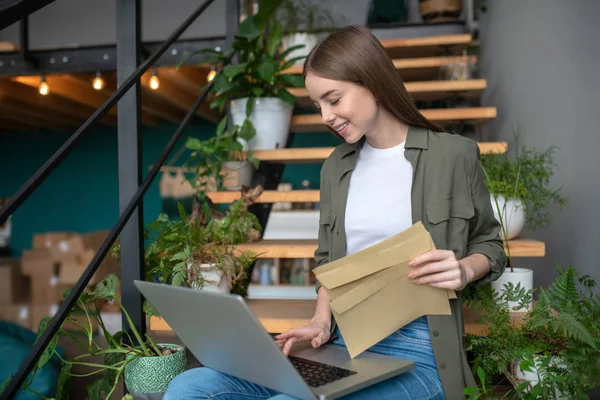 Жінка працює з комп'ютером і конвертами — стокове фото