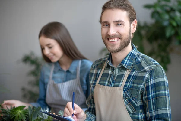 Lächelnder Mann macht sich in einem Pflanzenladen Notizen — Stockfoto