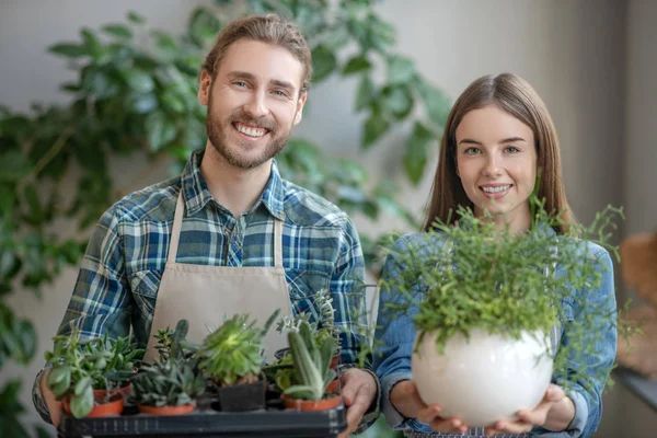 Man and woman holding various plants in hands — Stock Photo, Image