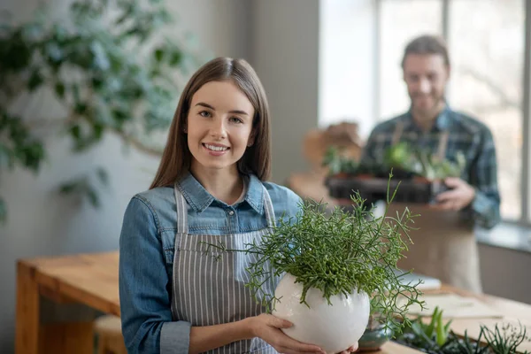 Mujer joven sosteniendo una olla con una planta — Foto de Stock