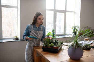 Elinde tabletle gülümseyen kadın lezzetlerini kontrol ediyor.