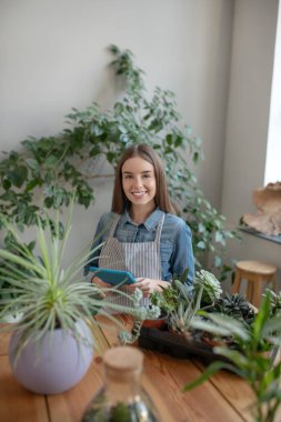Sulu bir evde tablet kullanan gülümseyen bir kadın.