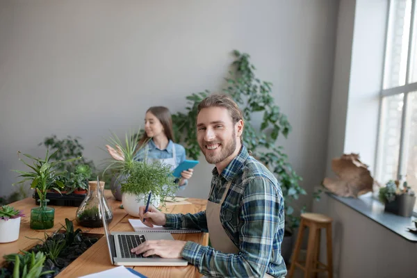 Smiling man taking notes from his laptop — 스톡 사진