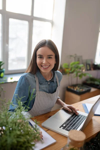 Leende kvinna som arbetar med en dator i en växtaffär — Stockfoto