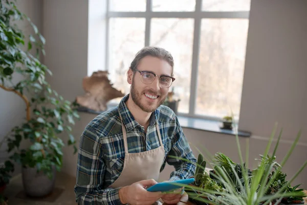 Homem sorridente usando um comprimido enquanto cuida das plantas — Fotografia de Stock