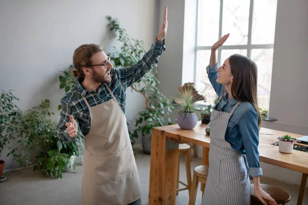 Homme et femme dans des tabliers faisant un high five — Photo