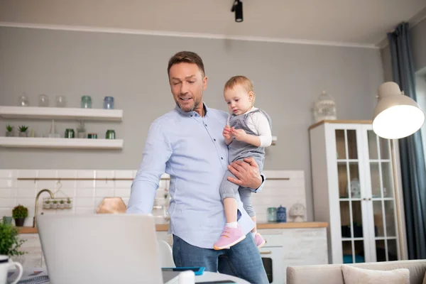 Mężczyzna w niebieskiej koszuli stojący i oglądający coś na laptopie — Zdjęcie stockowe