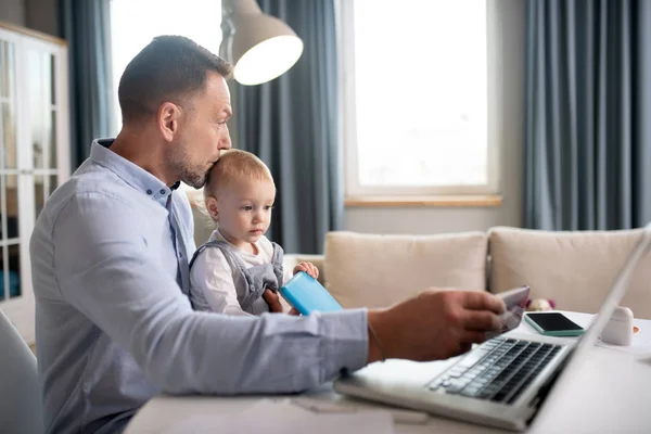 Man i blå skjorta arbetar och håller sin dotter — Stockfoto