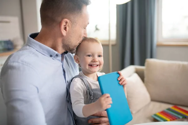 Man in een blauw shirt zoenen zijn baby meisje — Stockfoto