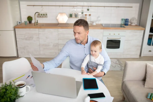 Mann im blauen Hemd sieht konzentriert aus, während er sich Video auf dem Tablet ansieht — Stockfoto