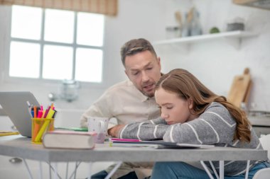 Gri gömlekli uzun saçlı kız depresyonda görünüyor.