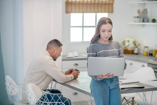 Chica de pelo largo en camisa gris leyendo algo en internet — Foto de Stock