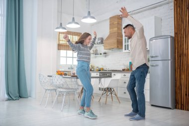 Gülümseyen baba ve kızı mutfakta dans ediyor..