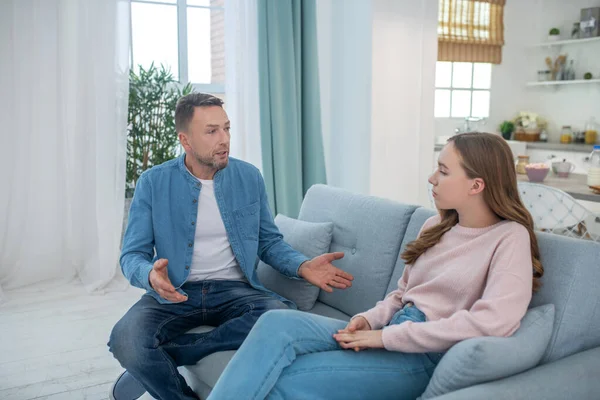 Papá hablando con la triste hija, ambos sentados en el sofá . — Foto de Stock