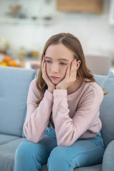 Nachdenklich trauriges Mädchen sitzt auf einem Sofa. — Stockfoto