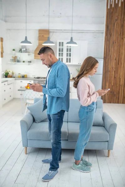 Father and daughter standing back to back near the sofa. — Stock Photo, Image