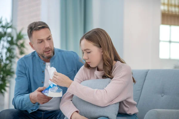 Vater beruhigt traurige Tochter, die beide auf der Couch sitzen. — Stockfoto