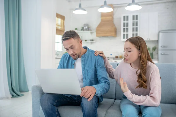 Father with laptop and daughter talking on the couch. — Stock Photo, Image