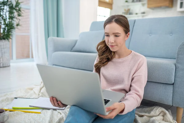 Flicka med en laptop i händerna sittande på golvet. — Stockfoto