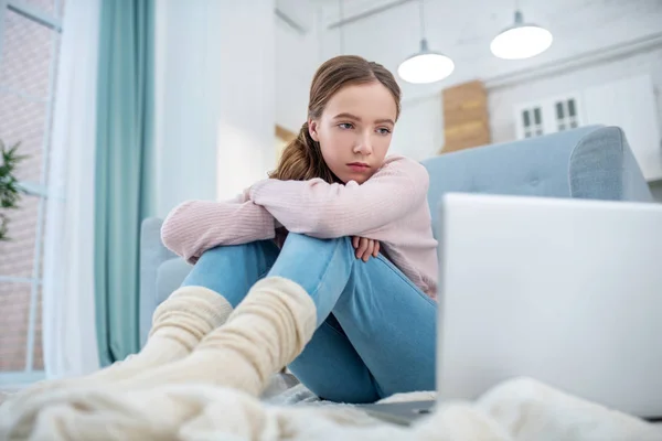 Nastolatka siedzi na podłodze patrząc na ekran laptopa. — Zdjęcie stockowe