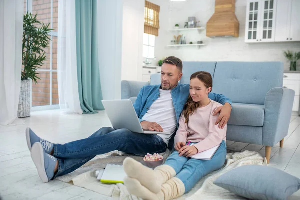 Dad and daughter sitting on the floor looking at a laptop. — Stock Photo, Image
