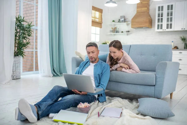 Pai com laptop no chão e filha no sofá . — Fotografia de Stock