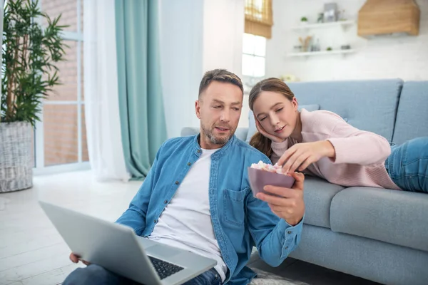 Dad with a laptop giving a marshmallow to his daughter. — Stock Photo, Image