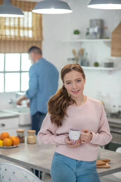 Радостная девушка с чашкой, стоящей на кухне . — стоковое фото