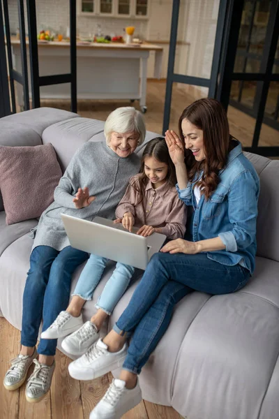 Chica, mamá, abuela charlando en línea en un ordenador portátil . — Foto de Stock