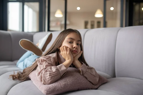 Gadis kecil yang sedih berbaring di sofa di rumah . — Stok Foto