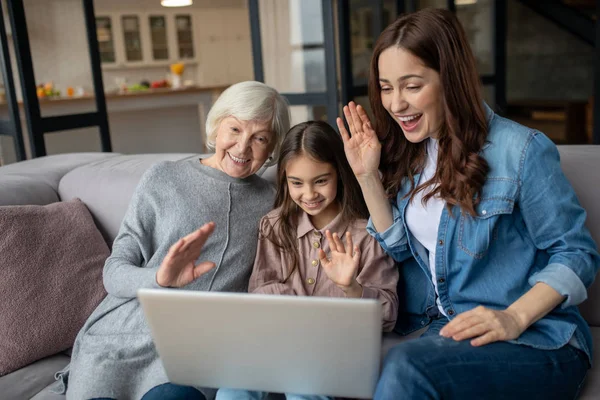 Daughter her mother and grandmother talking together online on a laptop.