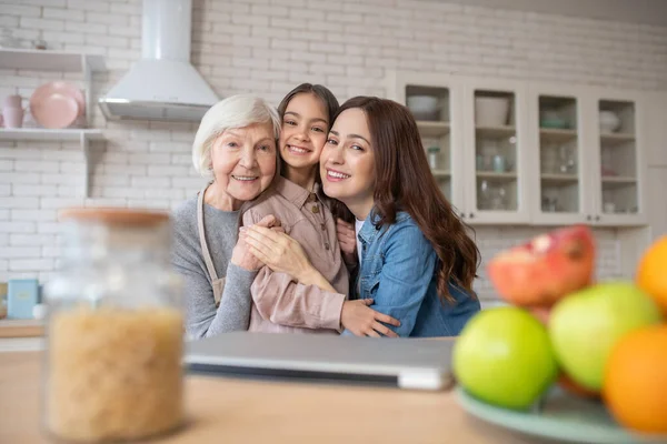 Young woman,elderly woman and little girl embraced smiling. — Stock Photo, Image