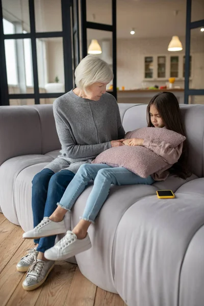Маленька дівчинка і її бабуся сидять на дивані . — стокове фото