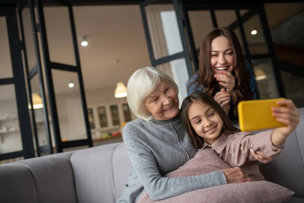 Menina tomando selfie com avó e mãe em casa . — Fotografia de Stock