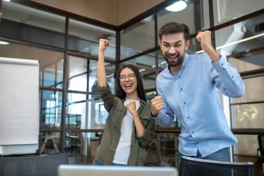 Uzun boylu genç adam ve bayan meslektaşı ofiste kendilerini harika hissediyorlar.