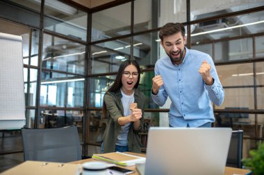 Uzun boylu genç adam ve bayan meslektaşı ofiste kendilerini başarılı hissediyorlar.