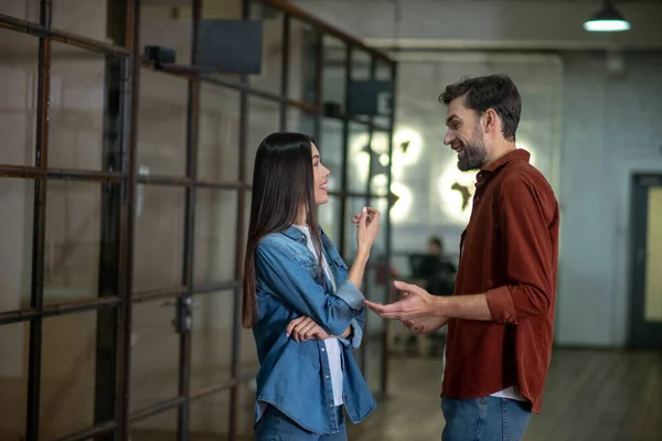 Baard knappe man in een bruin shirt bespreken iets met zijn vrouwelijke collega — Stockfoto